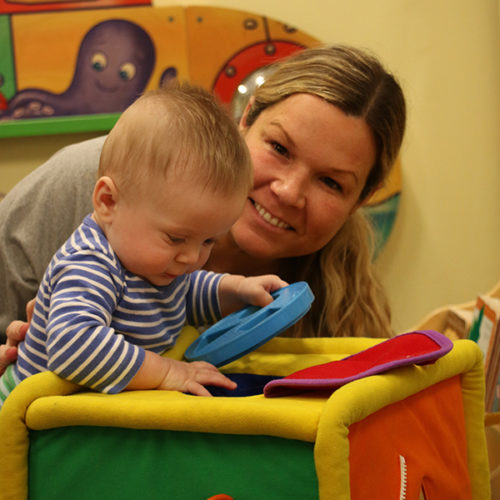 staff playing with infant holding toy shapes